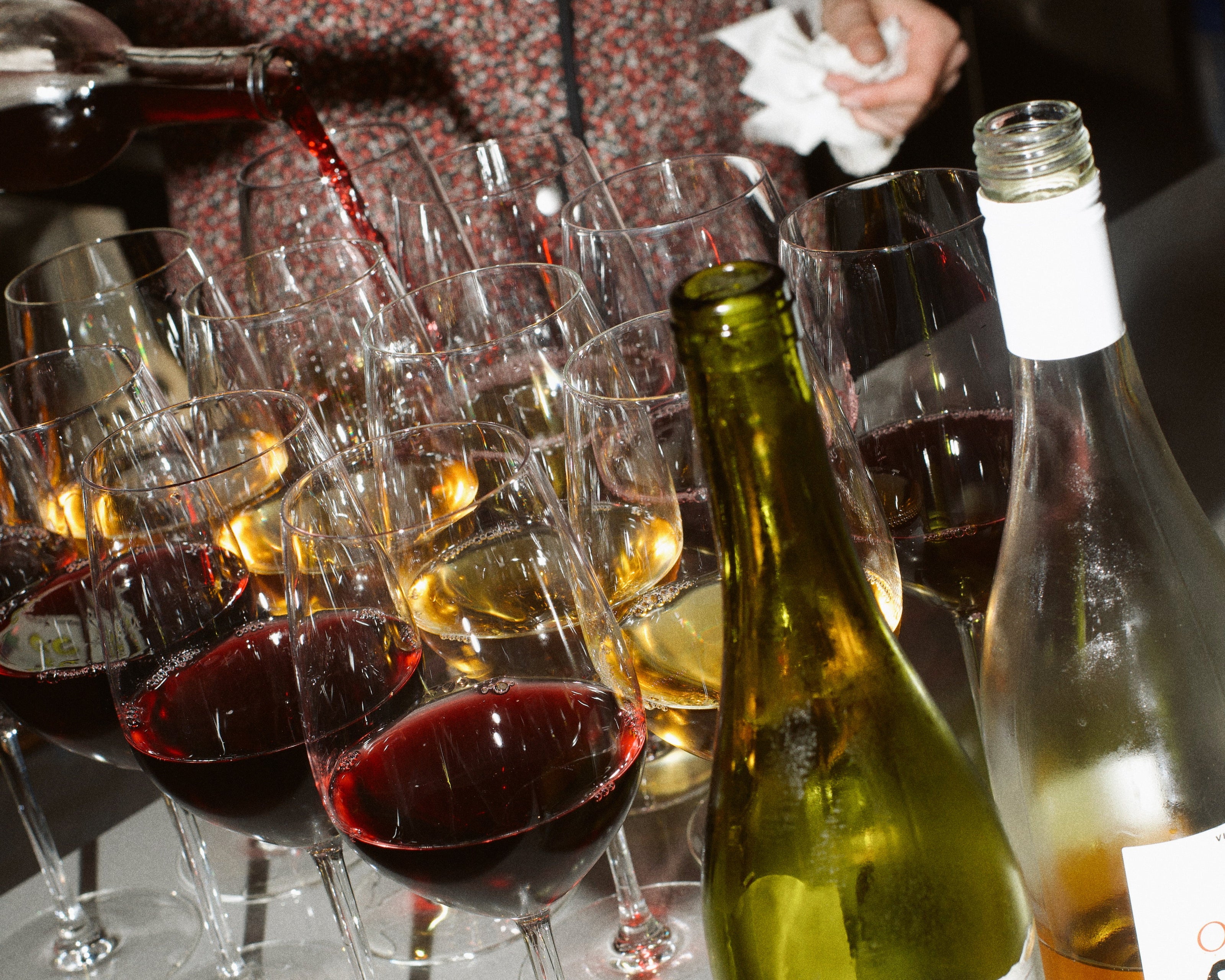 Wine bottles and glasses on a table with a person in the background.